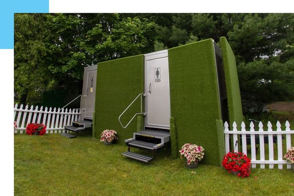 restroom trailer on grass with plants around