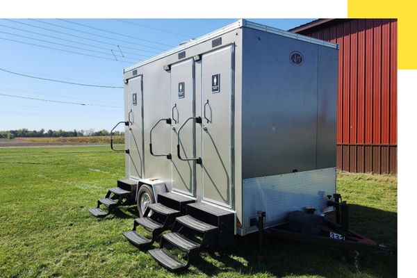 A luxury grey restroom trailer provided by an Allendale porta john company for an outdoor wedding.