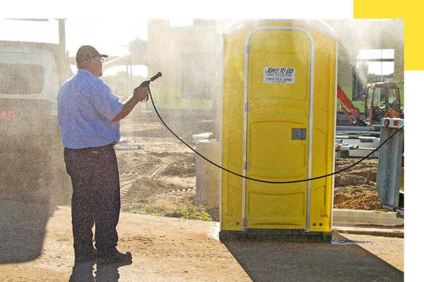 Spraying down a portable restroom