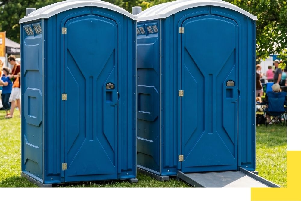 1:1 photograph showing two distinct unbranded portable restrooms—a standard unit and a larger, ADA-compliant unit with a ramp—set up side-by-side on a grassy lawn for an event, illustrating product versatility.